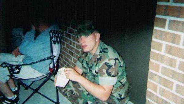 Stephan Jordan, a marine, crouched down eating a snack. 
