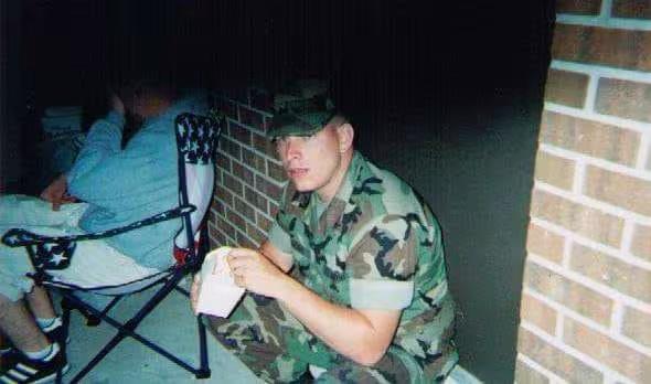 Stephan Jordan, a marine, crouched down eating a snack. 